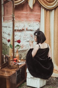 retro girl sitting at a dressing table and drinking alcohol from a glass