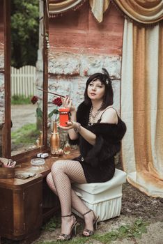 retro girl sitting at a dressing table, holding a candle and smoking cigarette with mouthpiece