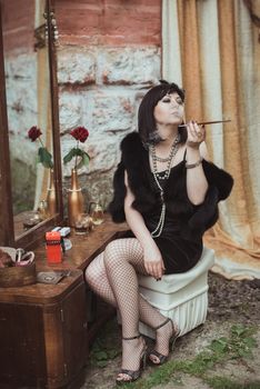 retro girl sitting at a dressing table and smoking cigarette with mouthpiece