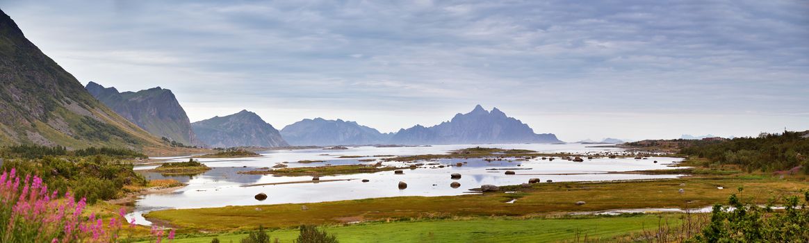 Norway landscape cloudy summer panorama, fjord and mountains in the background. Overcast sky