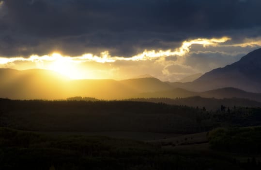 Orange sunset illuminating the clouds and mountains near the edge of the rockies