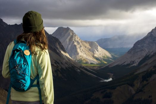 Brown haired girl looking out at monring sun illuminating mountains