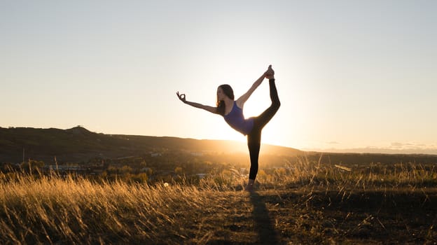Woman doing yoga dancers pose during evening sunset