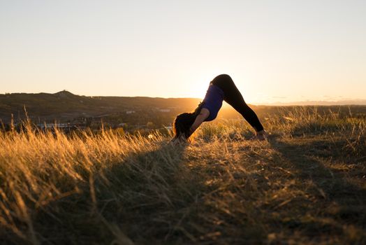 Woman doing yoga downward dog pose during evening sunset