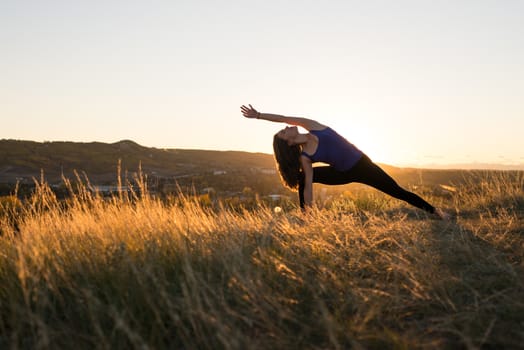 Woman doing yoga extended side angle pose during evening sunset