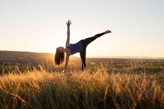 Woman doing yoga half moon pose during evening sunset