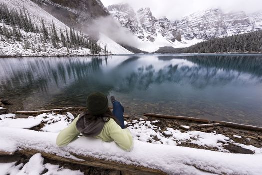 Girl taking in a scenic view of a blue lake in the snowy mountains