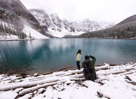 Photographer takes picture of female model next to beautiful lake in snow