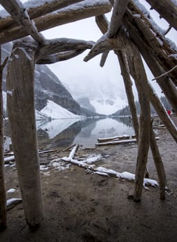 View of blue lake from inside a wooden hut snowy landscape