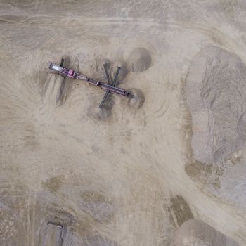 Aerial view of excavator and truck working on the field of sand mine in Poland.