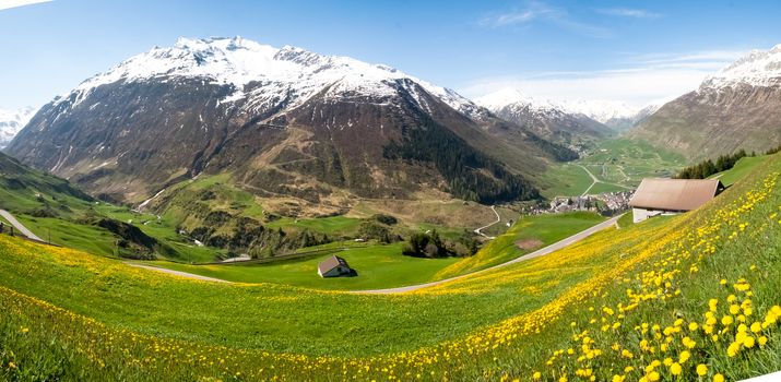 Andermatt, Switzerland: View of the pastures and mountains illuminated by the sun during a beautiful day on the day of the Feast of the Ascension