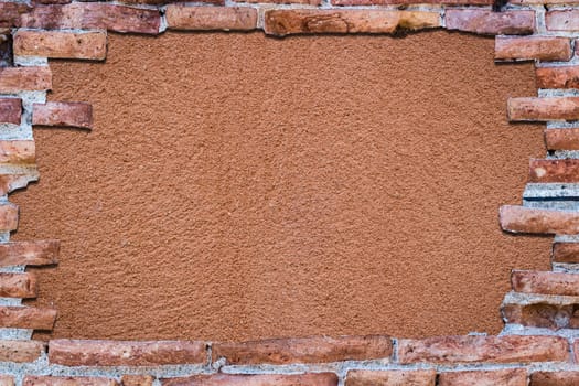 Ancient red brick wall with a hole over a bakground orange.