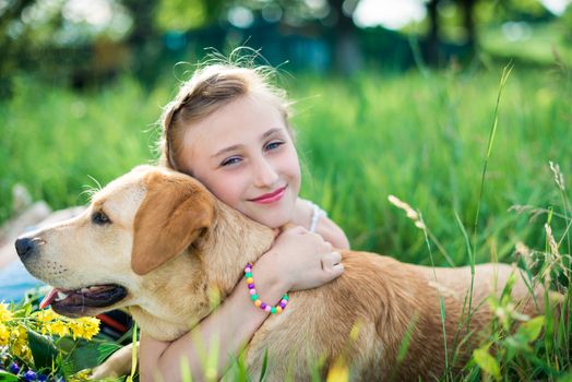 girl with a dog lying on the grass in the garden on a sunny summer day