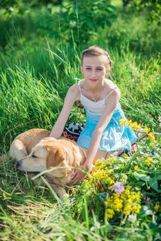 girl with a dog lying on the grass in the garden on a sunny summer day