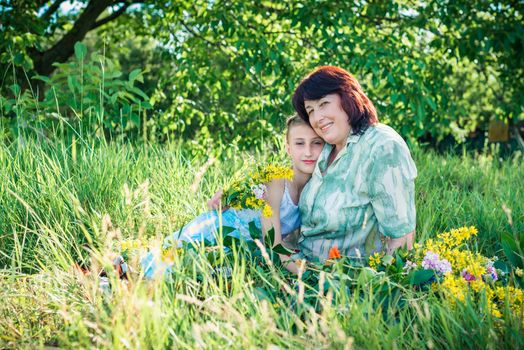 grandmother granddaughter with flowers in the green garden on a sunny summer day