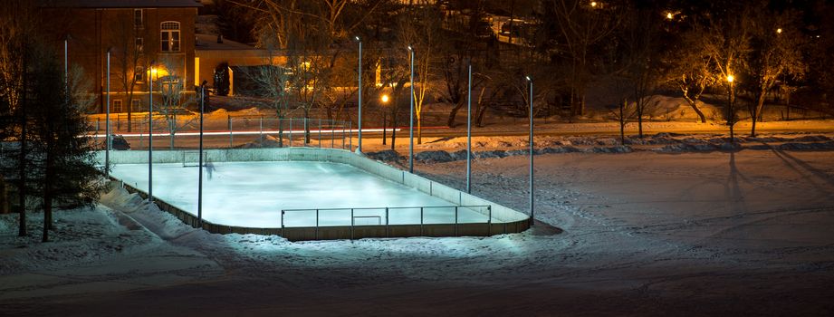 outdoor hockey rink in a field at night lit by lights
