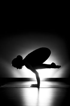 Woman doing yoga crow pose silhouette black and white in studio