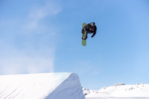 Snowboarder spinning doing a grab in the air off a jump