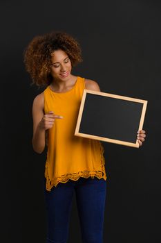 Beautiful African American woman showing something on a chalkboard