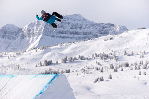 Snowboarder spinning doing a grab in the air off a jump