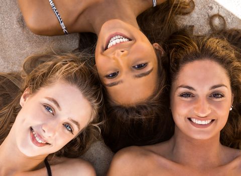 Top view portraits of three beautiful girls on the beach lying on the sand