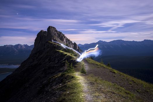 Light trail running along ridge of mountain lit up at night