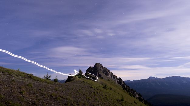 Light trail running along ridge of mountain lit up at night