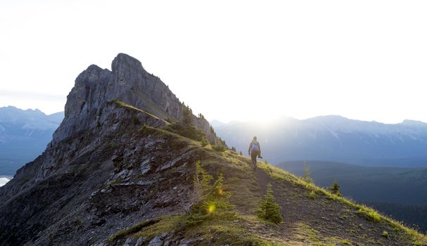 Male hiker walks along a ridge of mountain during sunrise