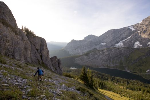 Male hiker walks along a ridge of mountain during sunrise