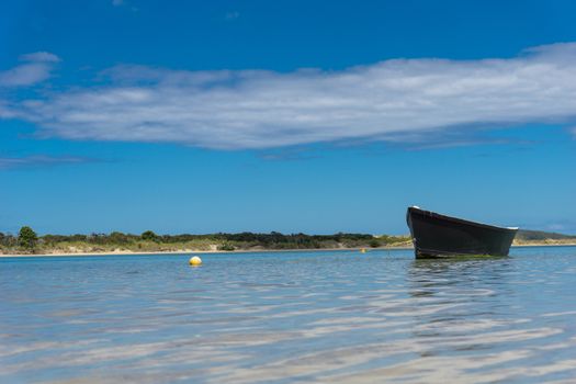 Blue dinghy water level point of view afloat on peaceful calm estuary Ngunguru  Northland New Zealand