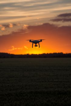 Drone silhouetted against orange sunset taking video