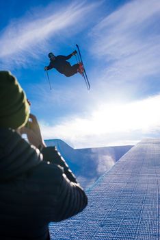 Photographer takes photo of halfpipe skier doing a grab trick