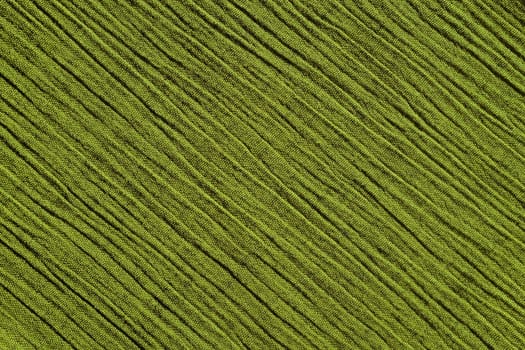 Light green crinkled fabric with irregular diagonal lines textile abstract background texture
