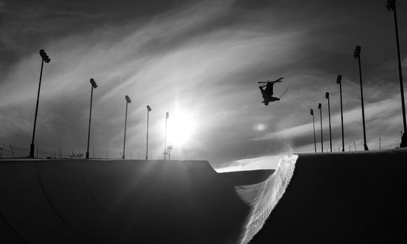 Skier doing an inverted trick in a winter snow halfpipe