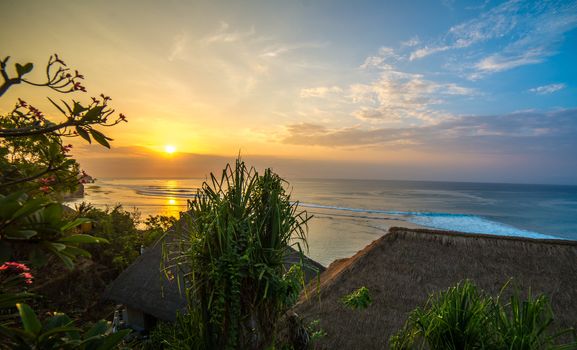 Surfers at sunset in Bali with straw roofed huts
