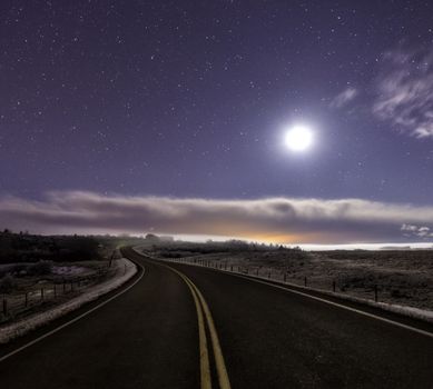Curved road lit up by the moon at nght
