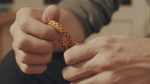 Man's hands tying a mountaineering knot on a rope. Close up.