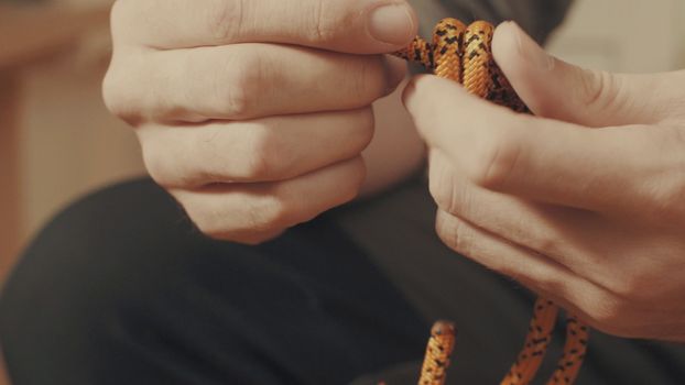 Man's hands tying a mountaineering knot on a rope. Close up.