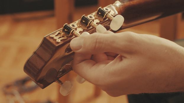 Guitarist's hands tuning the acoustic guitar close-up