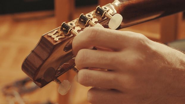 Guitarist's hands tuning the acoustic guitar close-up