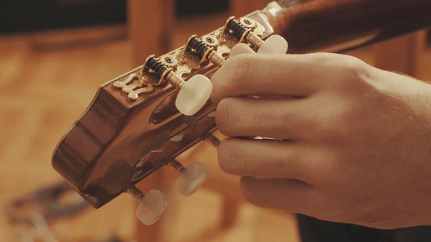 Guitarist's hands tuning the acoustic guitar close-up