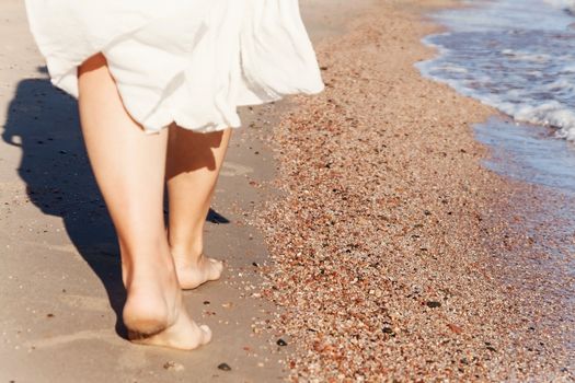 vacation travel - woman leg closeup walking on white sand relaxing in beach cover-up pareo beachwear. Sexy and tanned legs. Sunmmer holidays, weight loss or epilation, pedicure concept.