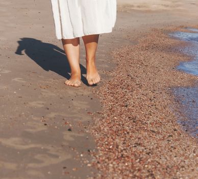 vacation travel - woman leg closeup walking on white sand relaxing in beach cover-up pareo beachwear. Sexy and tanned legs. Sunmmer holidays, weight loss or epilation, pedicure concept.