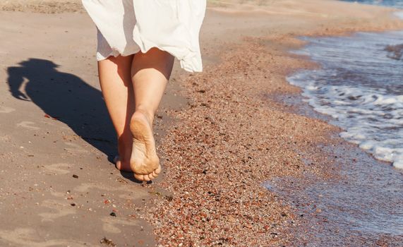 vacation travel - woman leg closeup walking on white sand relaxing in beach cover-up pareo beachwear. Sexy and tanned legs. Sunmmer holidays, weight loss or epilation, pedicure concept.