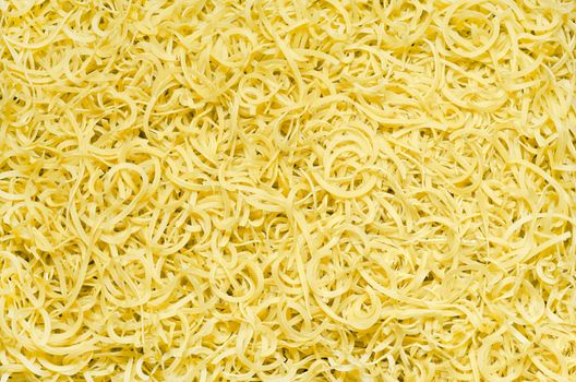 Textured background of small shaped pasta scattered on the surface, natural color.