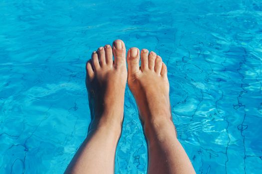 naked female legs on a background of blue water.