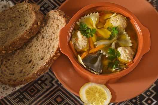 Italian soup in a ceramic pot and bread on an old embroidered towels. Low key, selective focus.