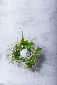 Egg and flowers on a white surface. Easter symbols.