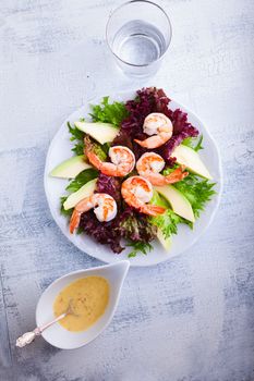 Avocado shrimp salad with mustard sauce on a white plate
