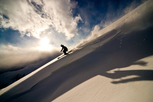 Freerider moving down a slope. Winter sunset in the mountains